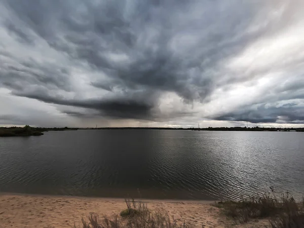 Üzerinde kara bulutların oluştuğu gölün dramatik bir görüntüsü.