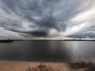 Üzerinde kara bulutların oluştuğu gölün dramatik bir görüntüsü..