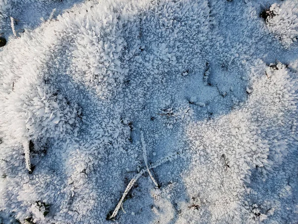 En vy över den ojämna ytan av jorden täckt med kristaller av frost på en frostig solig dag. — Stockfoto