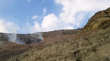 Yanan dağ yamaçlarında hareket eden bir arabanın yan penceresinden manzara..