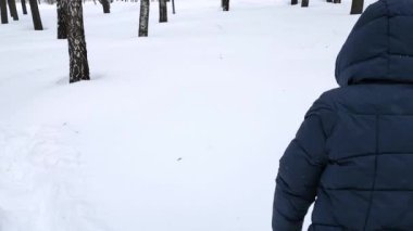 Mavi ceketli genç bir kadın parktaki devasa kar yığınlarında yürüyor..