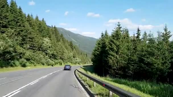 Austria. Eisenstadt 10.07.2019 Una vista a través del parabrisas de un coche hacia una carretera en las montañas a lo largo de la cual los coches conducen y se adelantan entre sí. — Vídeo de stock