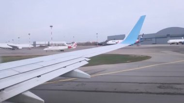 Uçak kabininden piste ve havaalanına giden uçağın kanadının görüntüsü..