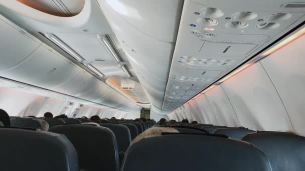 View of the aircraft cabin and the back side of the seats with people sitting in them — Stockvideo