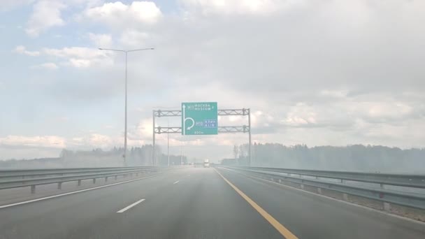 The car drives along the St. Petersburg Moscow Autobahn in a smoky area from a fire. — Stock Video