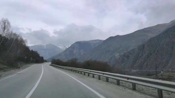 17.04.2021 Rusia. Baksan. Vista a través del parabrisas del coche en la carretera y los vehículos que pasan con una vista de la región de Elbrus. — Vídeo de stock