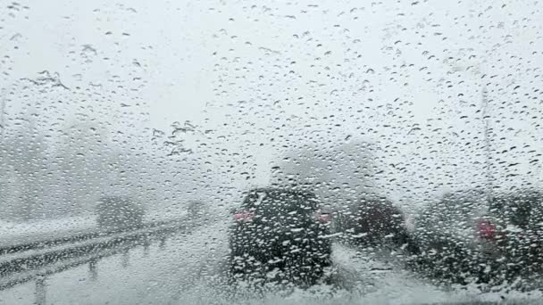 A view through the windshield of a car with drops from melted snow onto the road with cars in a traffic jam. — Stock Video