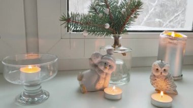 Pencerenin dışındaki karla kaplı ağaçların manzarasıyla evin pencere eşiğinde köknar ağacı kardan adam ve baykuşların Noel manzarası..