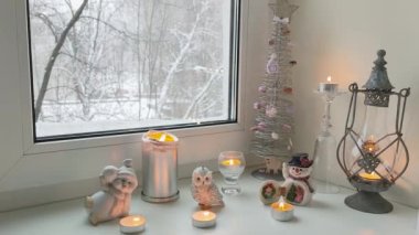 Pencerenin dışındaki karla kaplı ağaçların manzarasıyla evin pencere eşiğinde köknar ağacı kardan adam ve baykuşların Noel manzarası..