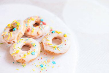 Hindistan cevizi şekerli donutlar, krema ve mermer zemin üzerine funfetti serpiştirilmiş.. 