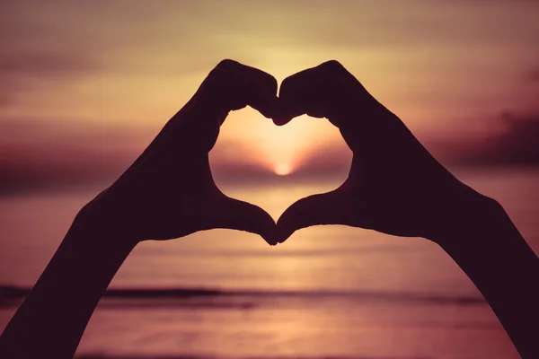 Símbolo de mano que significa amor al atardecer en la playa — Foto de Stock