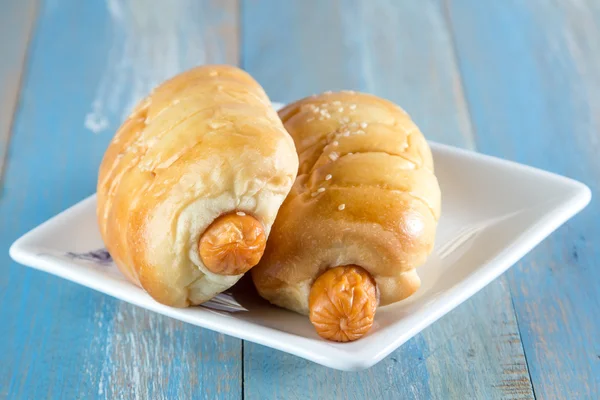 Pão com linguiça em prato em madeira — Fotografia de Stock