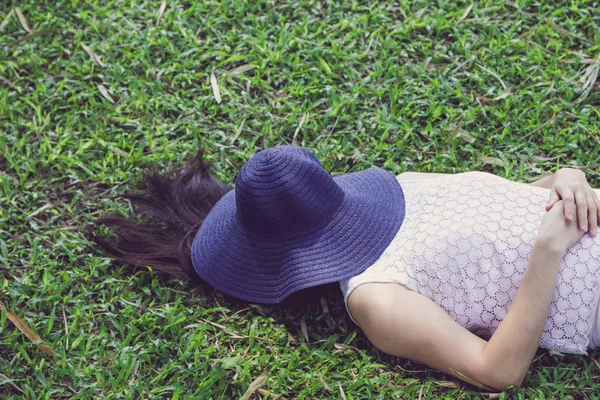 Woman sleeping with hat over face her on lawn — Stock Photo, Image