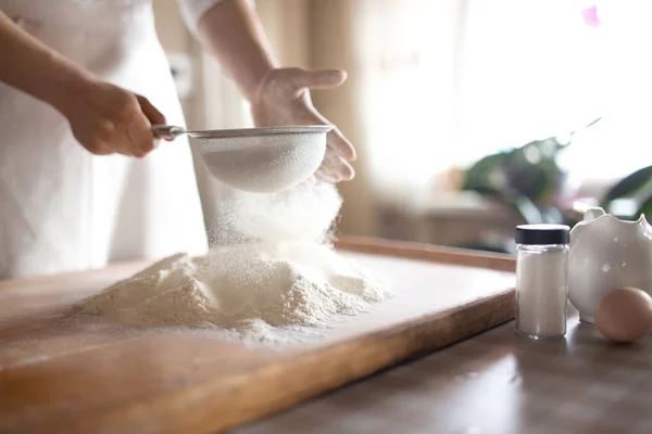 Jeune femme tamiser la farine dans un bol à la cuisine — Photo