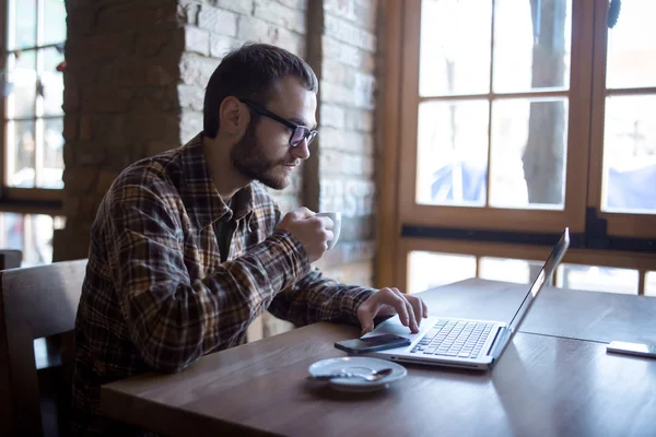 Genç adam sokakta tablet bilgisayar kullanırken kahve içme