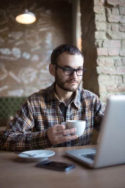 Genç adam sokakta tablet bilgisayar kullanırken kahve içme