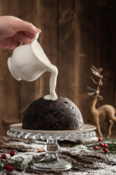 Sahne über Weihnachtspudding gießen — Stockfoto