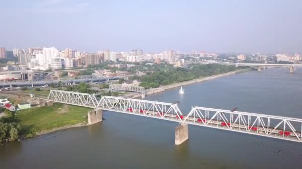 Elektryczny pociąg przekracza rzekę Ob. Pierwszy most kolejowy w Nowosybirsku. Panorama miasta Nowosybirsk. Rosja. 4K — Wideo stockowe