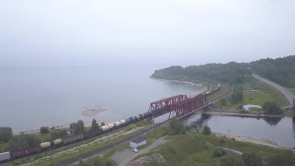 Trans-Siberische spoorweg, de kust van het Baikalmeer. Beweging van treinen op de ijzeren brug over de rivier die naar Baikal stroomt. 4K — Stockvideo