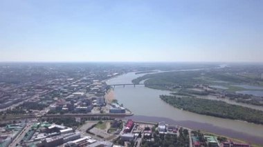 Irtysh ve Om nehirlerinin birleşmesi, şehrin panoramik manzarası. Omsk, Rusya. 4K
