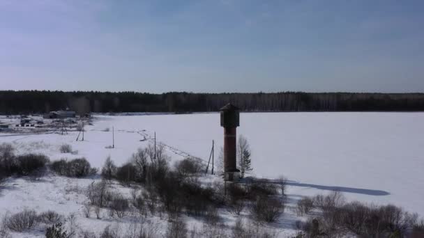 Flyger på vintern. Gamla vattentornet på ett snötäckt fält. 4K — Stockvideo