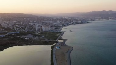 Novorossiysk, Rusya. Gün batımında şehrin manzarası. Şehir seti. Karadeniz 'deki Tsemesskaya Körfezi, Hava Görüntüsü  