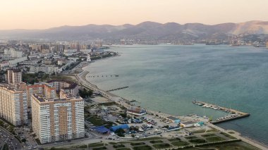 Novorossiysk, Rusya. Gün batımında şehrin manzarası. Şehir seti. Karadeniz 'deki Tsemesskaya Körfezi, Hava Görüntüsü  