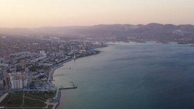 Novorossiysk, Rusya. Gün batımında şehrin manzarası. Şehir seti. Karadeniz 'deki Tsemesskaya Körfezi, Hava Görüntüsü  