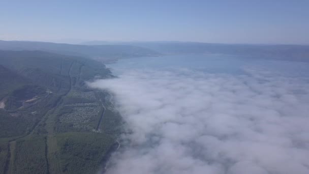 Voando acima das nuvens. Costa do Lago Baikal. Montanhas cobertas de floresta. A Rússia. 4K — Vídeo de Stock