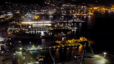 Novorossiysk, Rusya. Geceleyin Novorossiysk Limanı. Gece şehir ışıkları. Karadeniz 'deki Tsemesskaya Körfezi. 4K