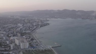Novorossiysk, Rusya. Gün batımında şehrin manzarası. Şehir seti. Karadeniz 'deki Tsemesskaya Körfezi. 4K