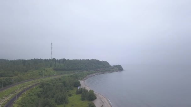 Rusland, Baikal. Trans-Siberische spoorweg, kust van het Baikalmeer. Treinverkeer langs de oever van het meer. 4K — Stockvideo