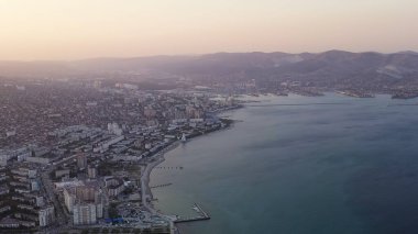 Novorossiysk, Rusya. Gün batımında şehrin manzarası. Şehir seti. Karadeniz 'deki Tsemesskaya Körfezi, Hava Görüntüsü  