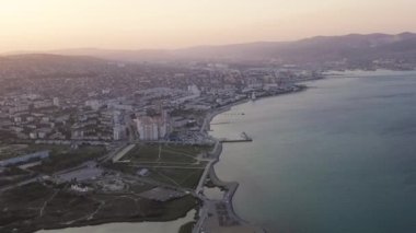 Novorossiysk, Rusya. Gün batımında şehrin manzarası. Şehir seti. Karadeniz 'deki Tsemesskaya Körfezi. 4K
