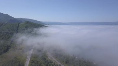 Bulutların üzerinde uçuyor. Baykal Gölü kıyısında. Ormanla kaplı dağlar. - Rusya. 4K