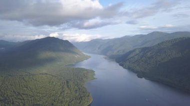 Teletskoye Gölü 'nün panoramik manzarası bulutlara tırmanıyor. Rusya, Altai. Ormanlarla kaplı dağlar. 4K
