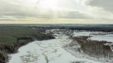 Dolly zoom. Dolly Zoom. Nehrin karanlık çizgileriyle karla kaplı bir bataklığın üzerinde uçuyorlar. Arka plandaki köy. Güneşin ışıkları. 4K