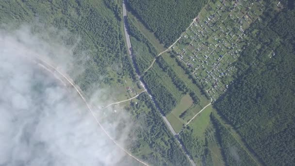 El tren se arrastra a lo largo del ferrocarril bajo las nubes a lo largo de la costa. Transibir ferrocarril. Carretera. Volando sobre las nubes. Costa del Lago Baikal.. 4K — Vídeo de stock