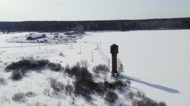 Voler en hiver. Ancien château d'eau sur un champ enneigé. 4K — Video