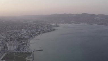 Novorossiysk, Rusya. Gün batımında şehrin manzarası. Şehir seti. Karadeniz 'deki Tsemesskaya Körfezi. 4K