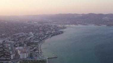 Novorossiysk, Rusya. Gün batımında şehrin manzarası. Şehir seti. Karadeniz 'deki Tsemesskaya Körfezi. 4K