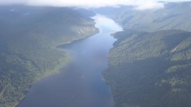 Teletskoye Gölü 'nün panoramik manzarası bulutlara tırmanıyor. Rusya, Altai. Ormanlarla kaplı dağlar. 4K