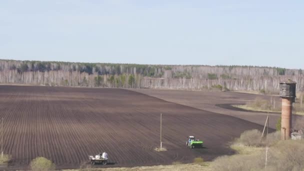 ドリーズームだ。ロシア、ウラル。畑にジャガイモをコンバインとトラクターで植える。春 — ストック動画