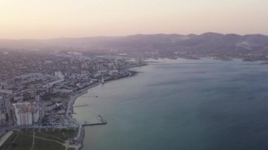 Novorossiysk, Rusya. Gün batımında şehrin manzarası. Şehir seti. Karadeniz 'deki Tsemesskaya Körfezi. 4K