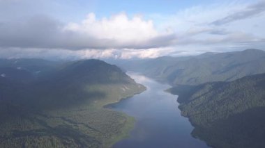 Teletskoye Gölü 'nün panoramik manzarası bulutlara tırmanıyor. Rusya, Altai. Ormanlarla kaplı dağlar. 4K