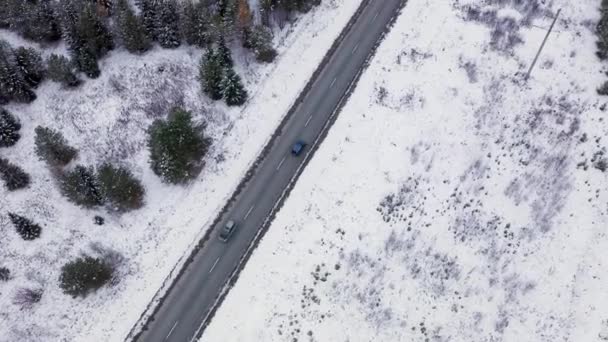 Um carro azul está dirigindo ao longo de uma estrada de asfalto de inverno. A estrada vai ao longo das linhas de energia. Neve nas árvores e nas estradas. 4K — Vídeo de Stock