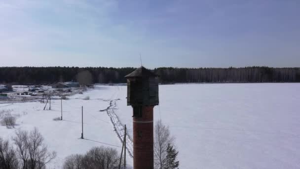 Flyger på vintern. Gamla vattentornet på ett snötäckt fält. 4K — Stockvideo