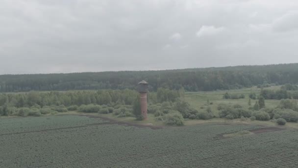 Rusya, Ural. Tarlaların üzerinde uçuyor. Patates yetiştirme sıraları. Eski kırmızı tuğlalı su kulesi. 4K — Stok video