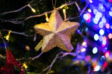 Altın parıltı, cam top ve altın top Noel ağacında seçici odak altında ve bazı bölgelerde bulanık.