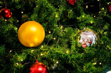 Altın parıltı, cam top ve altın top Noel ağacında seçici odak altında ve bazı bölgelerde bulanık.